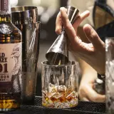 Un barista prepara un bourbon drink versando il Wild Turkey 101 in un bicchiere con ghiaccio.