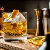 Cocktail con ghiaccio, scorza d'arancia e fette d'arancia. Ingredienti per un drink giapponese, con bottiglia di whisky e jigger in rame.