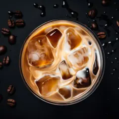 Un delizioso caffè freddo al bar, con cubetti di ghiaccio e latte che creano un vortice invitante. Chicchi di caffè tostati completano la scena.