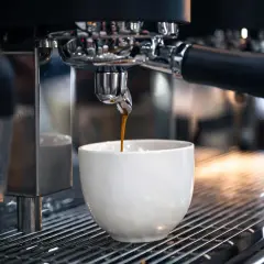 Un espresso scuro gocciola in una tazza bianca. Sorprendentemente, il caffè contiene glutine, un dettaglio che molti ignorano.