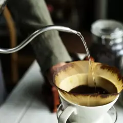 Preparazione di un v60 caffè: acqua calda versata lentamente su caffè macinato in un filtro di carta.