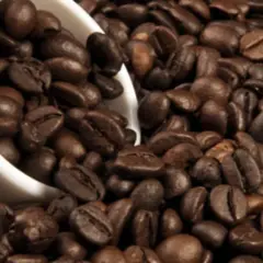 Chicchi di caffè tostati, una tazza bianca rovesciata. La caffeina, una droga che risveglia i sensi.