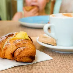 Un cornetto con crema e una tazza di cappuccino, un classico per la colazione italiana a casa.