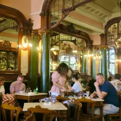 Interno di un **majestic cafe porto** con arredi d'epoca, specchi e clienti seduti ai tavoli.