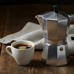 Moka vs espresso: una tazzina di caffè fumante accanto alla classica caffettiera italiana, pronta per un risveglio aromatico.