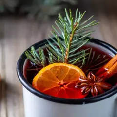 Un bicchiere di punch caldo, con arancia, cannella e anice stellato, decorato con un rametto di pino. Perfetto per le serate invernali.