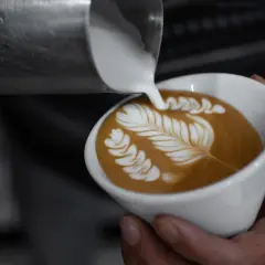 Chiara Bergonzi crea un capolavoro di latte art, versando schiuma cremosa su un caffè per formare un disegno a foglia.