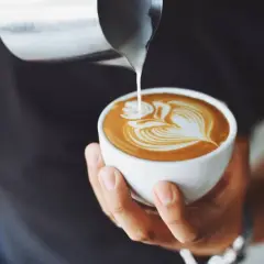 Un barista crea un disegno a latte art su un cappuccino, un'opera d'arte cremosa.