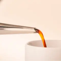 Caffè caldo versato da una cuccuma napoletana in una tazza bianca.