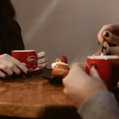 Due donne gustano un delizioso caffè e un dolce, condividendo un momento di relax.