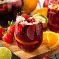 Sangria ricetta: bicchieri pieni di sangria con fragole, arance e lime. Frutta fresca intorno.