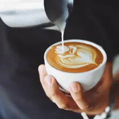 Un barista versa latte montato su un espresso, creando un disegno di latte art. Ecco come si fa il cappuccino perfetto.