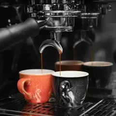 Caffè appena erogato in tazze colorate, un rituale quotidiano che richiede un decalcificante naturale per la macchina del caffè.