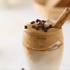 Un delizioso caffè freddo, con schiuma cremosa, gocce di cioccolato e un bastoncino di cannella.