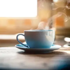 Tazza azzurra fumante su un tavolo di legno. Nonostante il suo aspetto invitante, il caffè è cancerogeno.