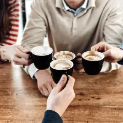 Amici brindano con diversi tipi di caffè al bar, con schiuma artistica e latte macchiato.