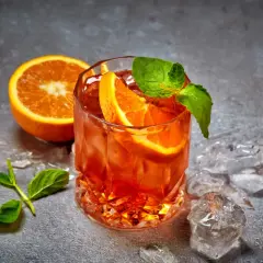 Rinfrescante cocktail con ghiaccio tritato, arancia e menta. Perfetto per un aperitivo estivo.