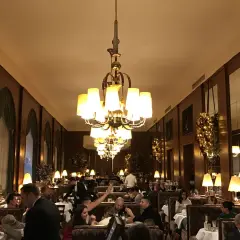Interno elegante di uno dei caffè storici di Vienna, con tavoli apparecchiati, clienti e lampadari imponenti.