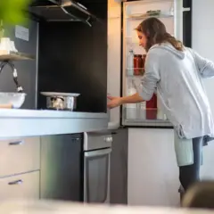 Donna prende una bottiglia dal frigo. Forse cerca il caffè in frigo per preparare una bevanda rinfrescante.