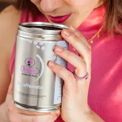 Donna annusa una lattina di caffè decaffeinato, godendosi l'aroma. Un caffè con meno caffeina, perfetto per ogni momento.