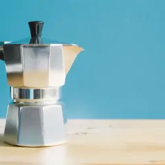 Moka italiana in alluminio, con manico nero, pronta per preparare un caffè. I suoi componenti sono ben visibili.