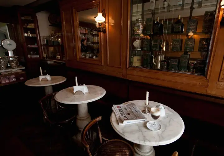 Un tavolino in marmo con un caffè, giornale e candela, in un antico caffè torinese.