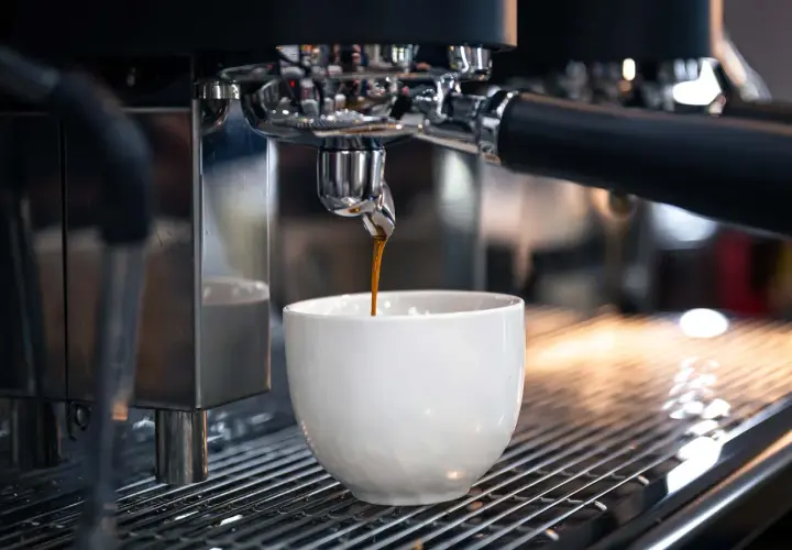 Un espresso scuro gocciola in una tazza bianca. Sorprendentemente, il caffè contiene glutine, un dettaglio che molti ignorano.