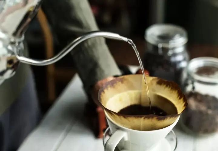 Preparazione di un v60 caffè: acqua calda versata lentamente su caffè macinato in un filtro di carta.