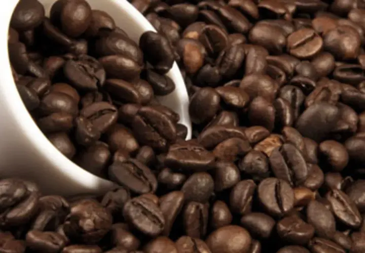 Chicchi di caffè tostati, una tazza bianca rovesciata. La caffeina, una droga che risveglia i sensi.