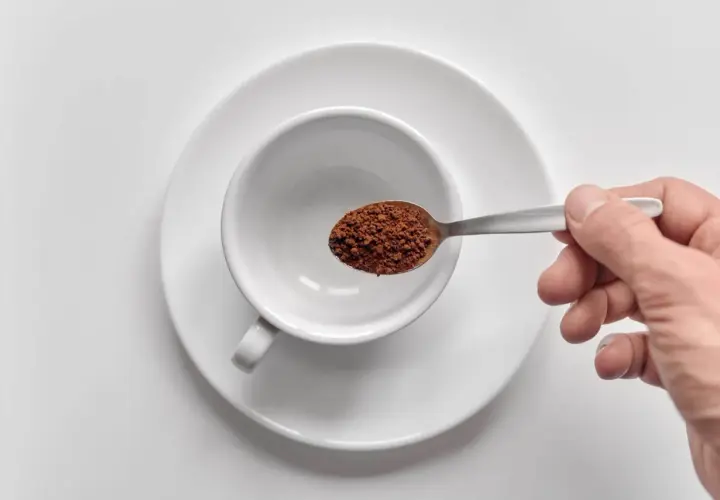 Mano che versa orzo café in una tazzina bianca.