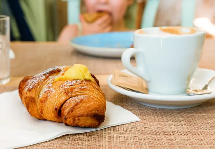 Un cornetto con crema e una tazza di cappuccino, un classico per la colazione italiana a casa.