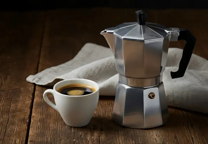 Moka vs espresso: una tazzina di caffè fumante accanto alla classica caffettiera italiana, pronta per un risveglio aromatico.