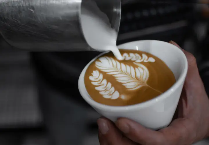Chiara Bergonzi crea un capolavoro di latte art, versando schiuma cremosa su un caffè per formare un disegno a foglia.