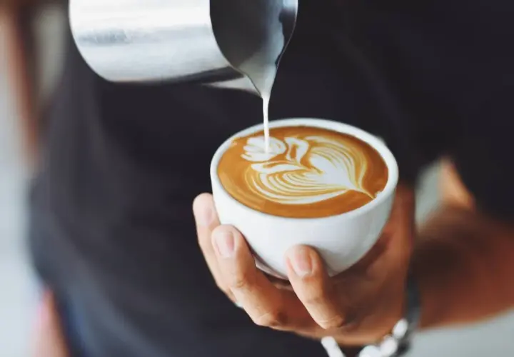 Un barista crea un disegno a latte art su un cappuccino, un'opera d'arte cremosa.