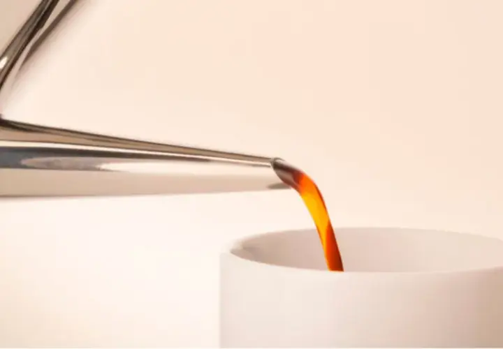 Caffè caldo versato da una cuccuma napoletana in una tazza bianca.