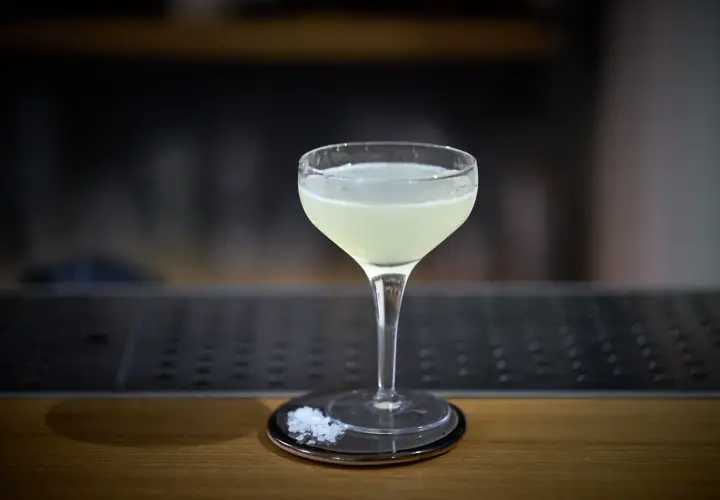 Un bicchiere di cocktail aspri, con sale grosso sul piattino, pronto per essere gustato.