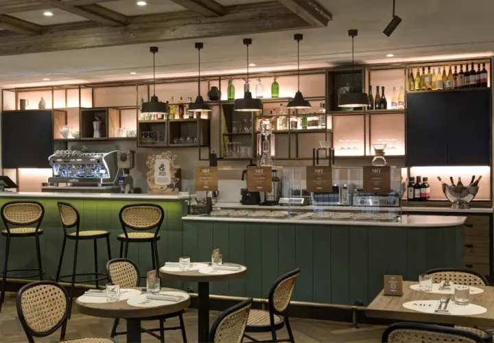 Interno di un locale moderno con bancone, macchine da caffè e tavoli. Un'atmosfera perfetta per gustare un ottimo caffè a Roma, famoso in tutto il mondo.
