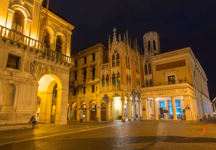 Edificio storico illuminato di notte a Padova, con archi e dettagli gotici. Un luogo che evoca il fascino di un **caffè storico Padova**.