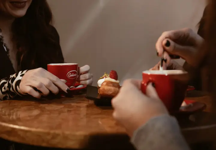 Due donne gustano un delizioso caffè e un dolce, condividendo un momento di relax.