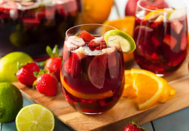 Sangria ricetta: bicchieri pieni di sangria con fragole, arance e lime. Frutta fresca intorno.
