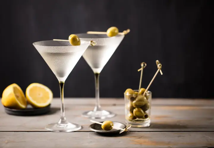 Due bicchieri di Martini, guarniti con olive, pronti per essere gustati. La martini ricetta IBA è un classico intramontabile.