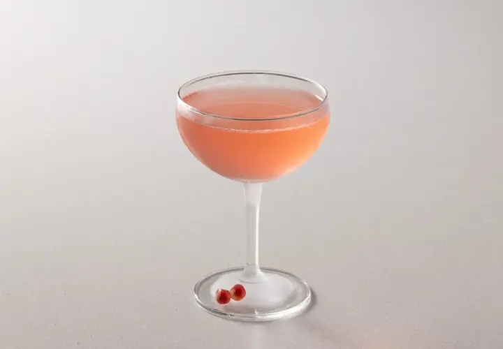 Cocktail rosa in coppa, perfetto per la tua bacardi cocktail ricetta. Due chicchi di melograno sul piattino.