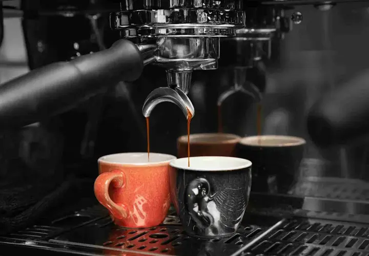 Caffè appena erogato in tazze colorate, un rituale quotidiano che richiede un decalcificante naturale per la macchina del caffè.