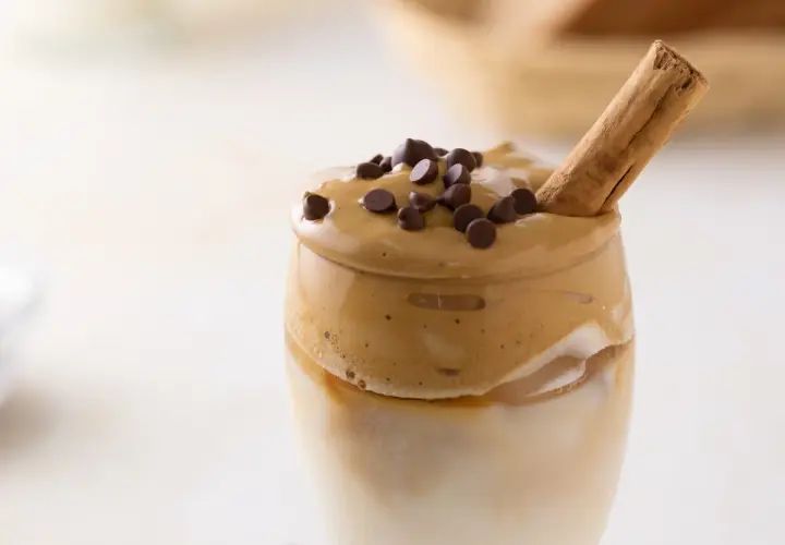 Un delizioso caffè freddo, con schiuma cremosa, gocce di cioccolato e un bastoncino di cannella.