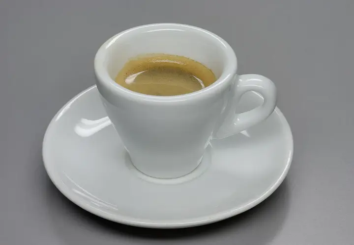 Tazza bianca con caffè espresso e crema, un omaggio a chi ha inventato il caffè espresso.