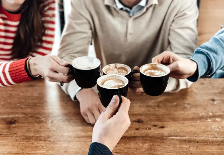 Amici brindano con diversi tipi di caffè al bar, con schiuma artistica e latte macchiato.