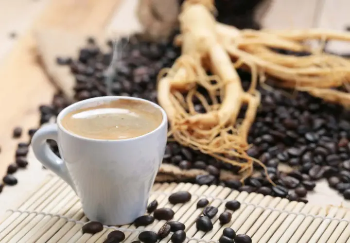 Tazza di caffè fumante accanto a chicchi tostati e radice di ginseng, che contiene caffeina per un risveglio energico.