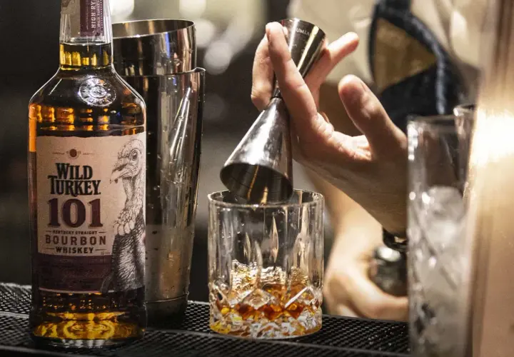 Un barista prepara un bourbon drink versando il Wild Turkey 101 in un bicchiere con ghiaccio.