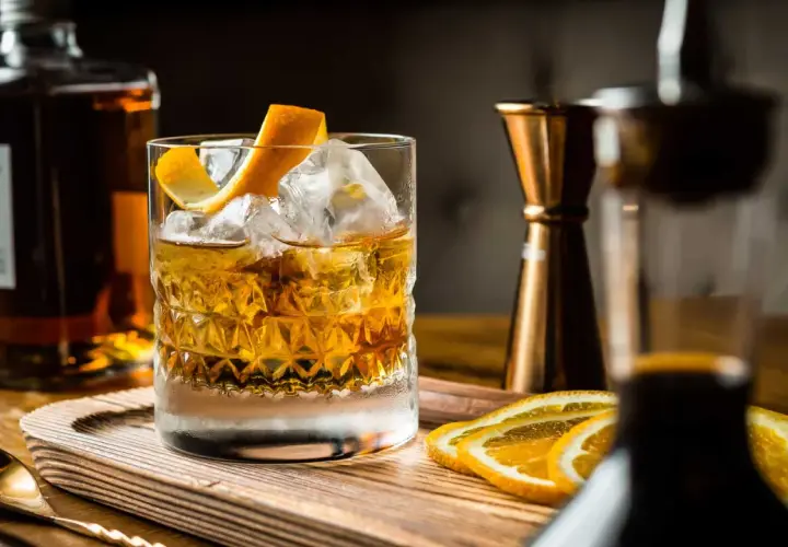 Cocktail con ghiaccio, scorza d'arancia e fette d'arancia. Ingredienti per un drink giapponese, con bottiglia di whisky e jigger in rame.
