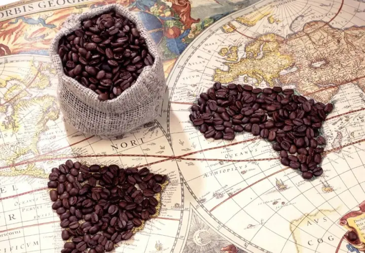 Chicchi di caffè su una mappa antica, che evocano il viaggio e la scoperta di chi ha inventato il caffè.